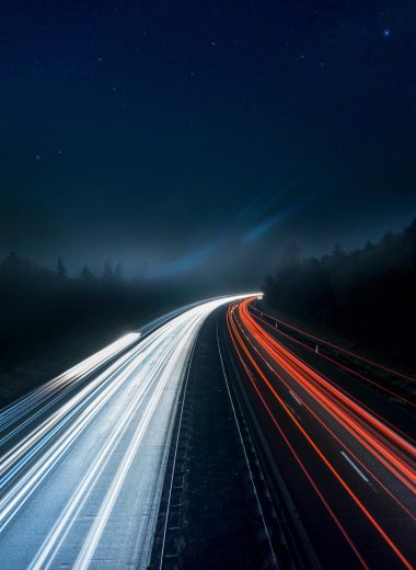 Light trails on a highway symbolizing acceleration, irreversible decision-making, and leadership under systemic pressure